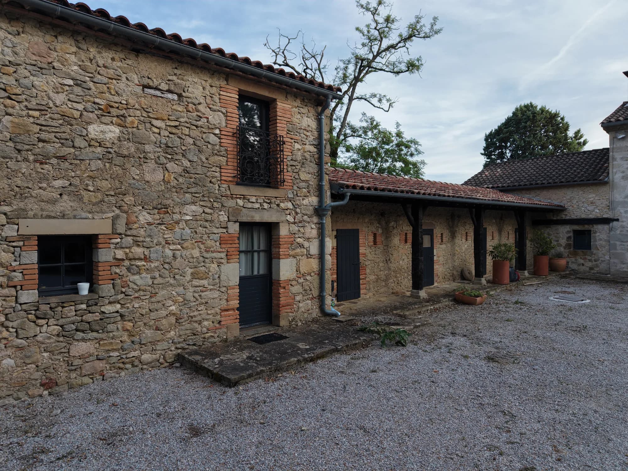 La cour et les façades en pierre, sous le préau