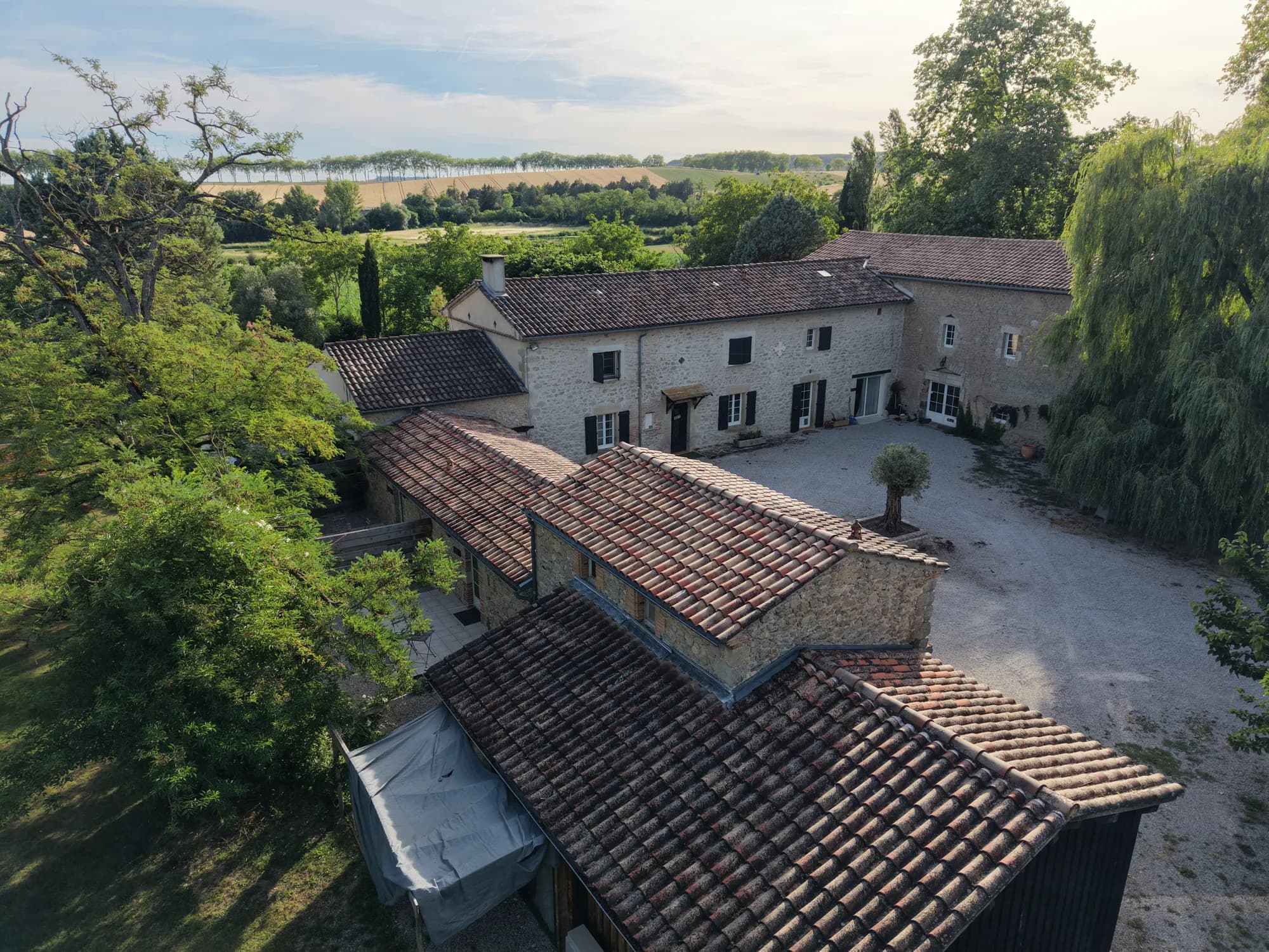 Vue aérienne du domaine : la bâtisse en pierre et ses dépendances, nichées dans la nature